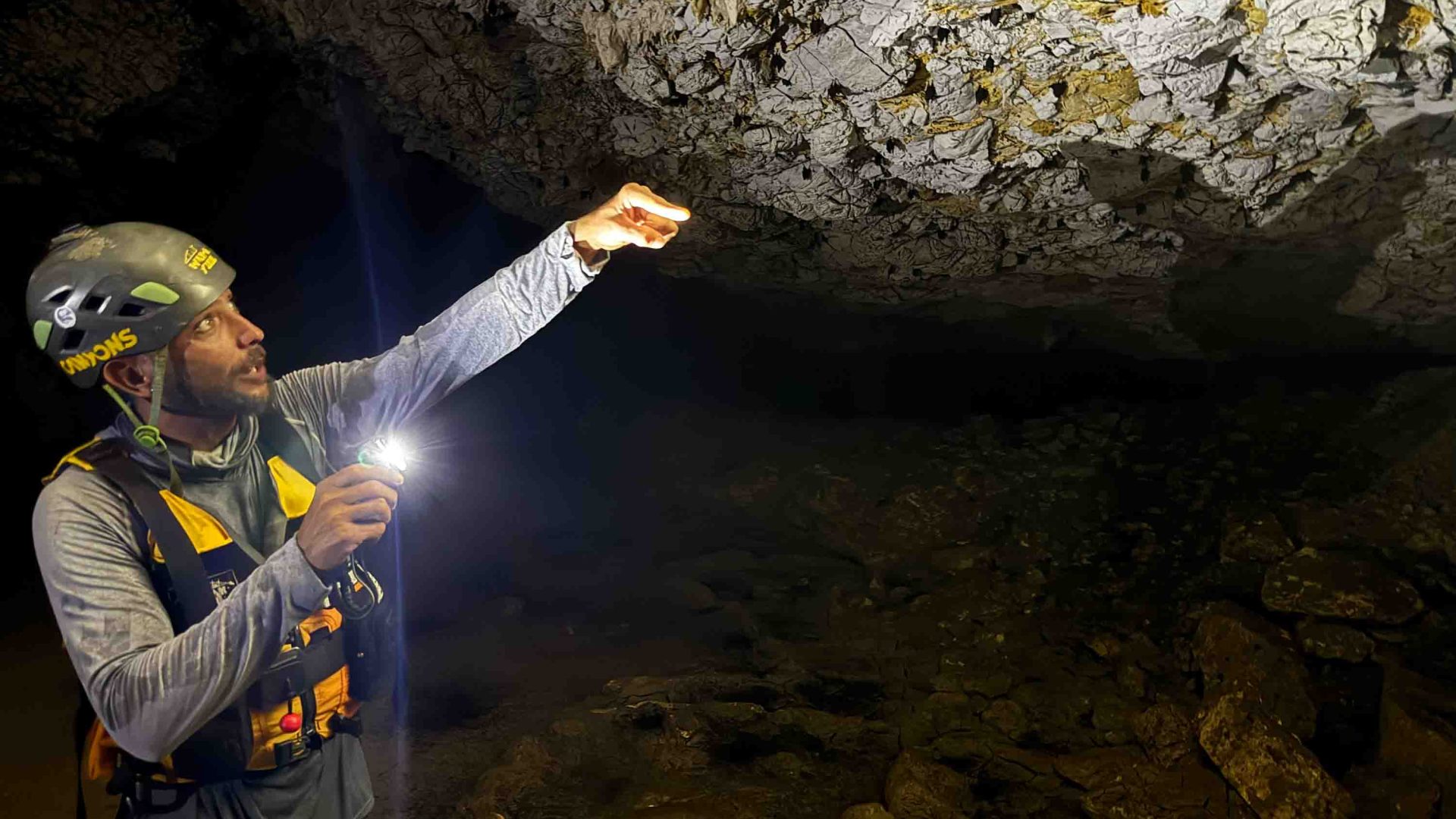 A man points up at a cave.
