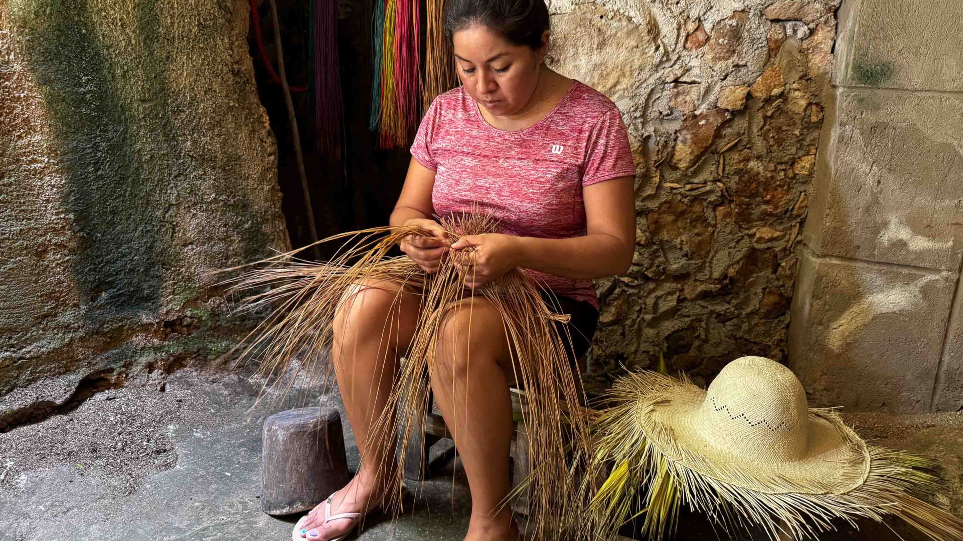 A woman makes hats underground in a cave.