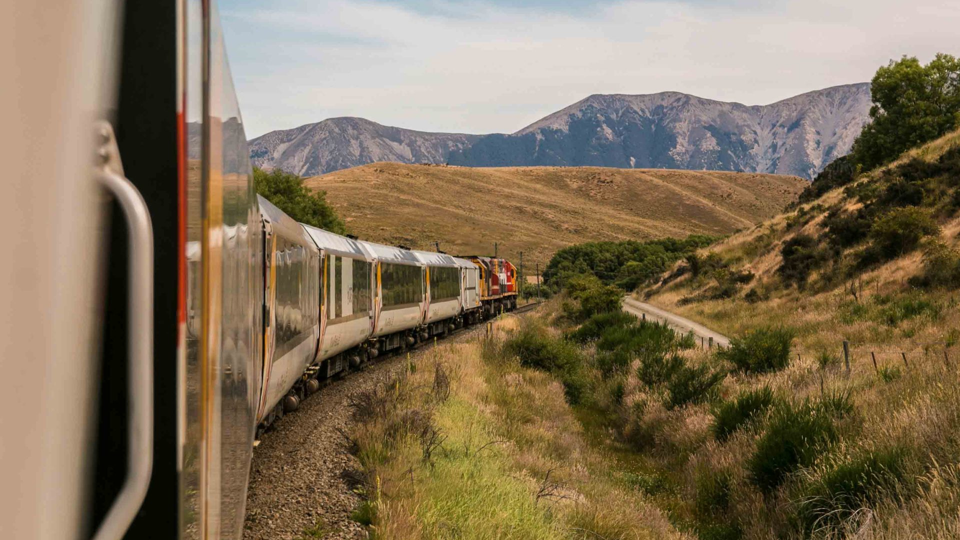 A train winds past hills.
