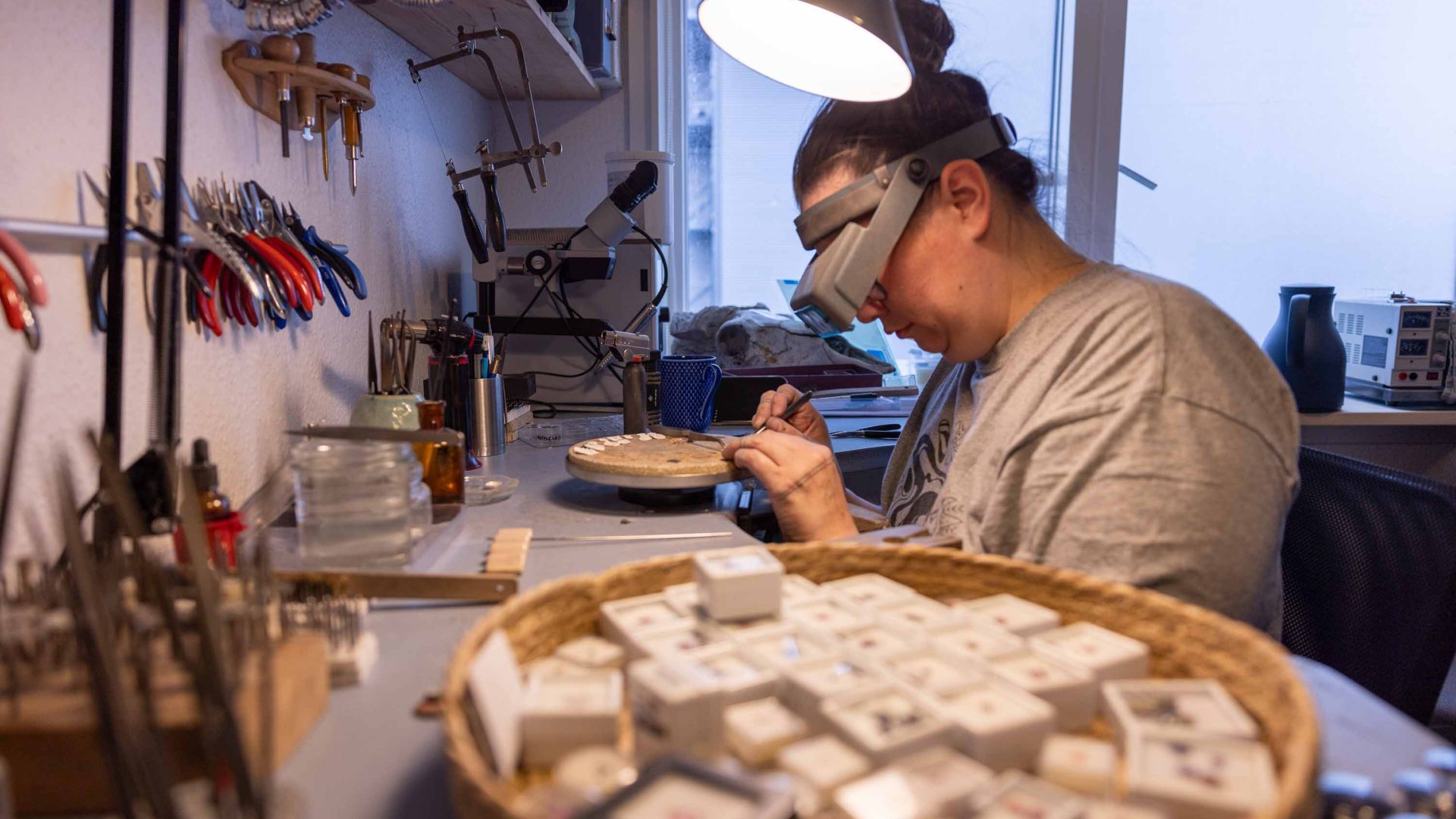 A woman wears protective glasses while making jewellery in a workshop.