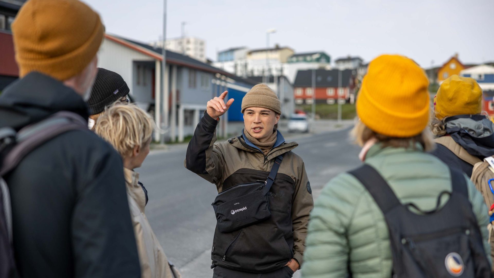 A guide talks to a group in front of a colourful town.