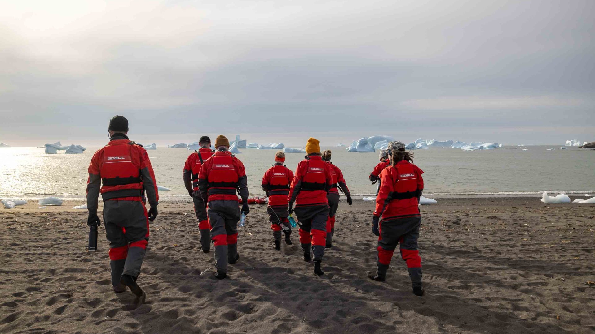A group in red walks toward the icebergs.