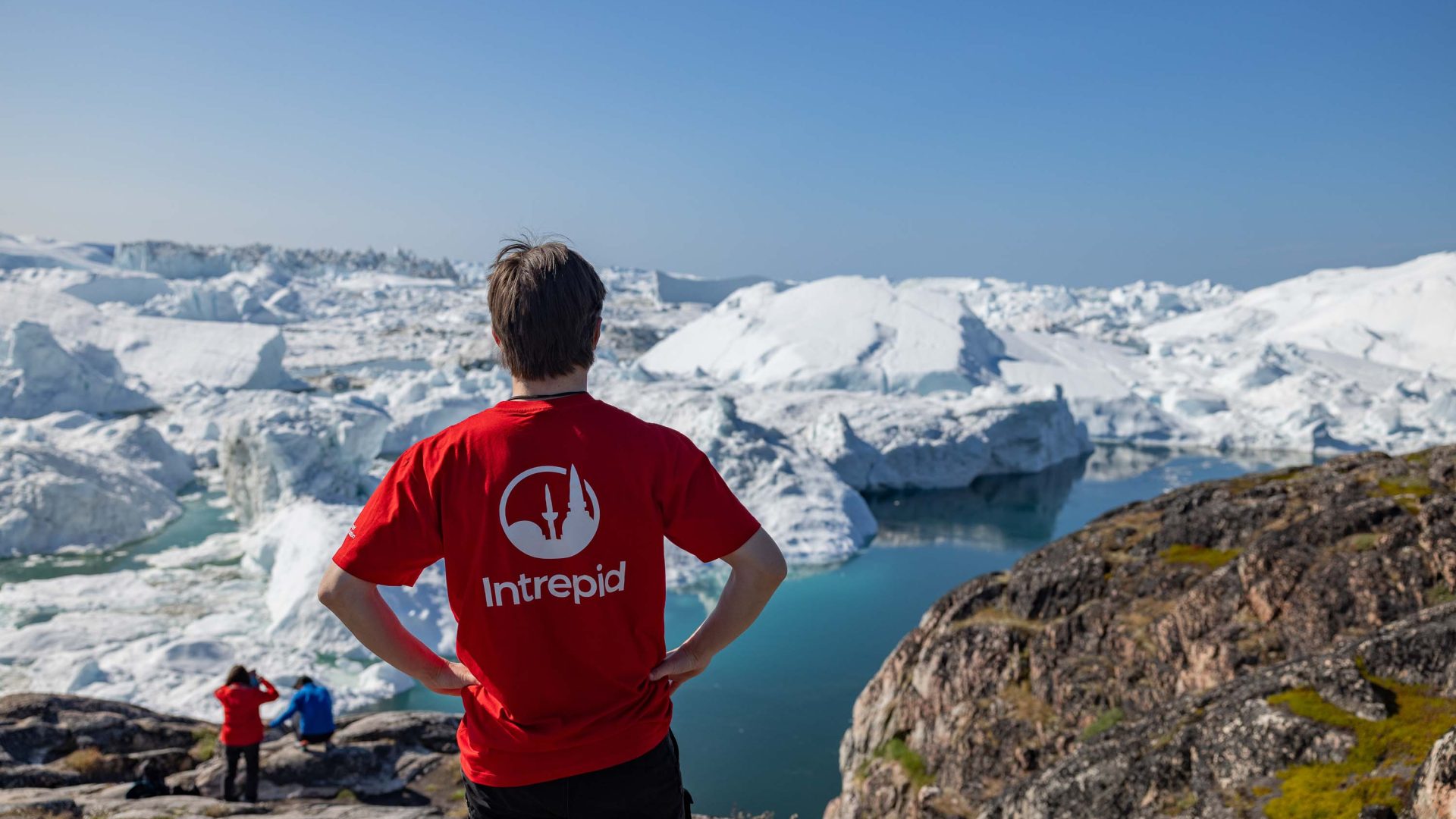 An Intrepid leader looks out over icebergs and water.