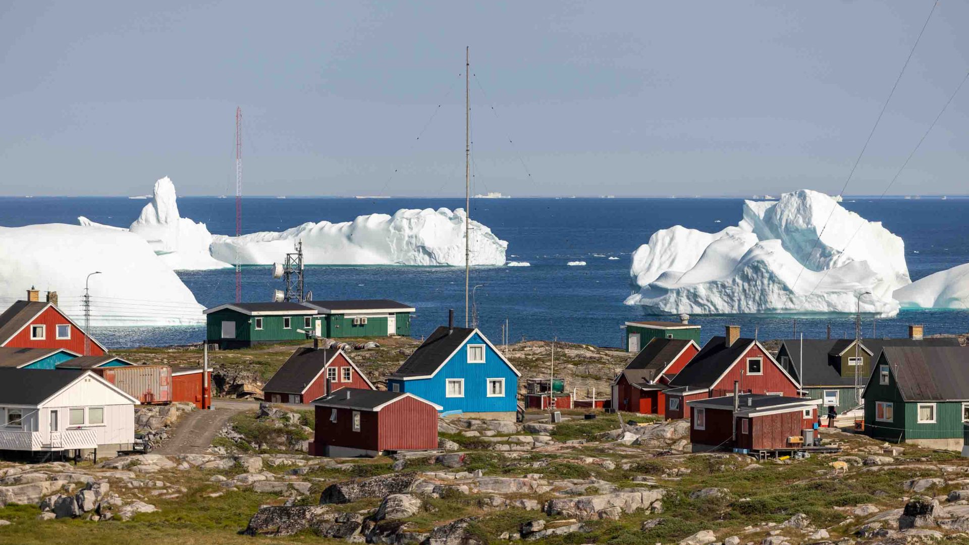 Colourful houses in front of water and icebergs.
