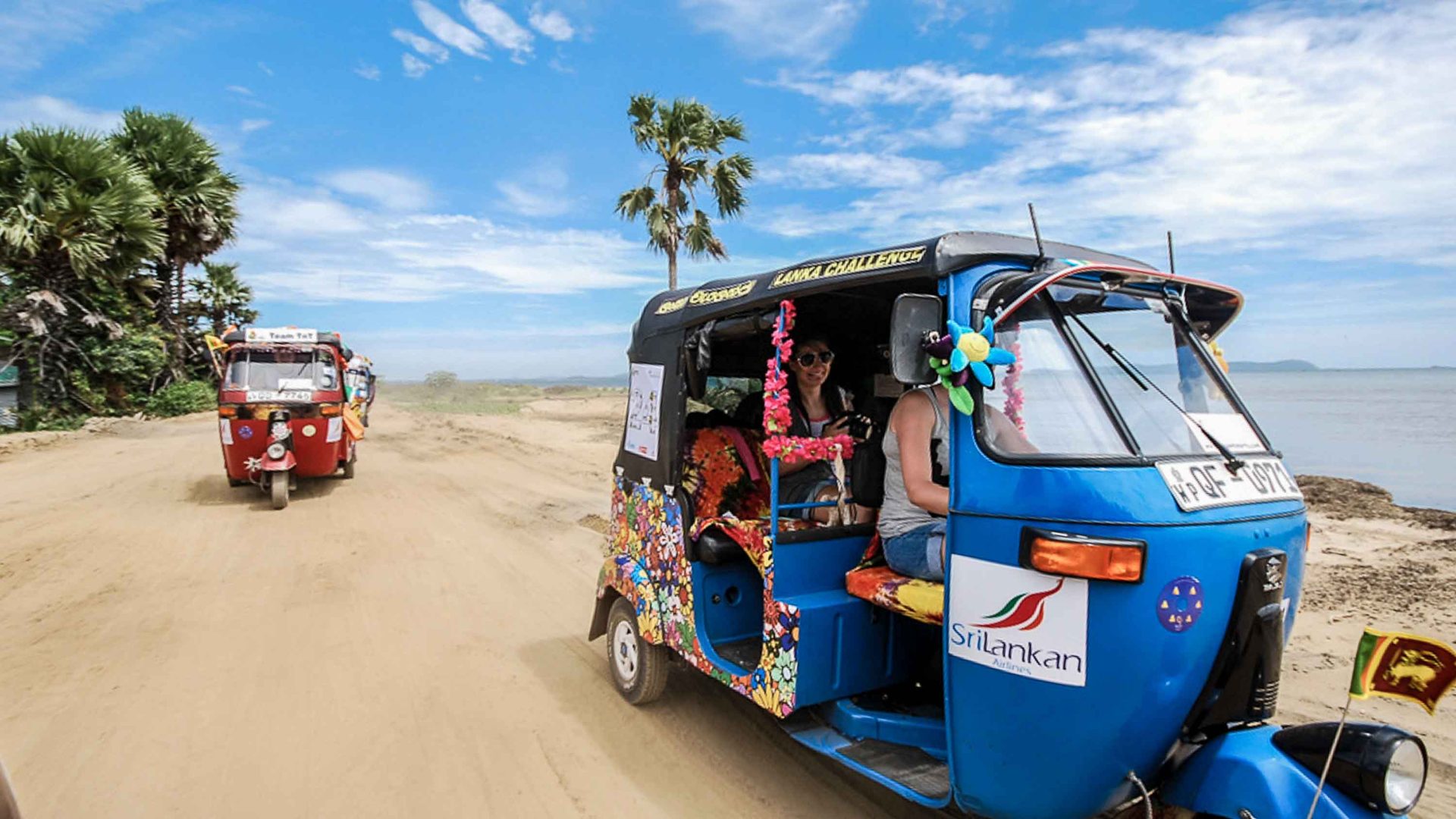 Two tuk tuks on a dusty road.