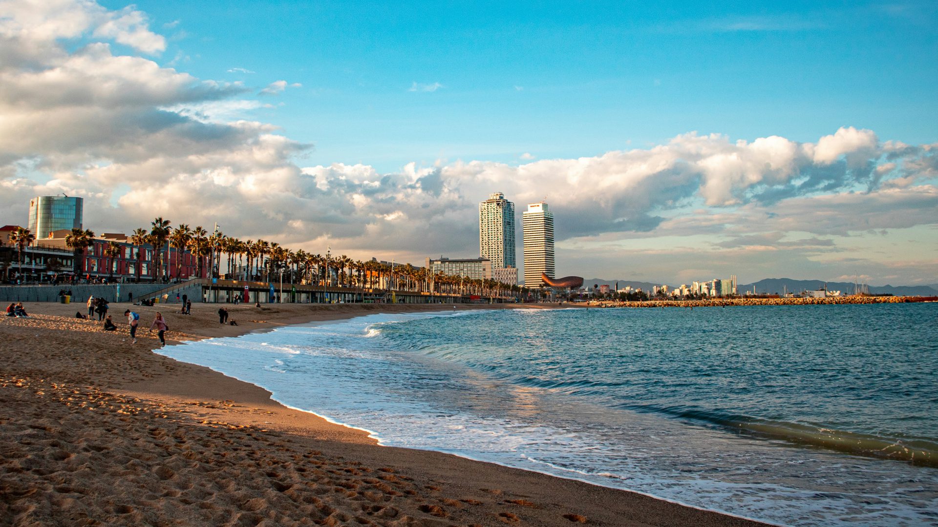 A beach in soft light with buildings on the coastline.