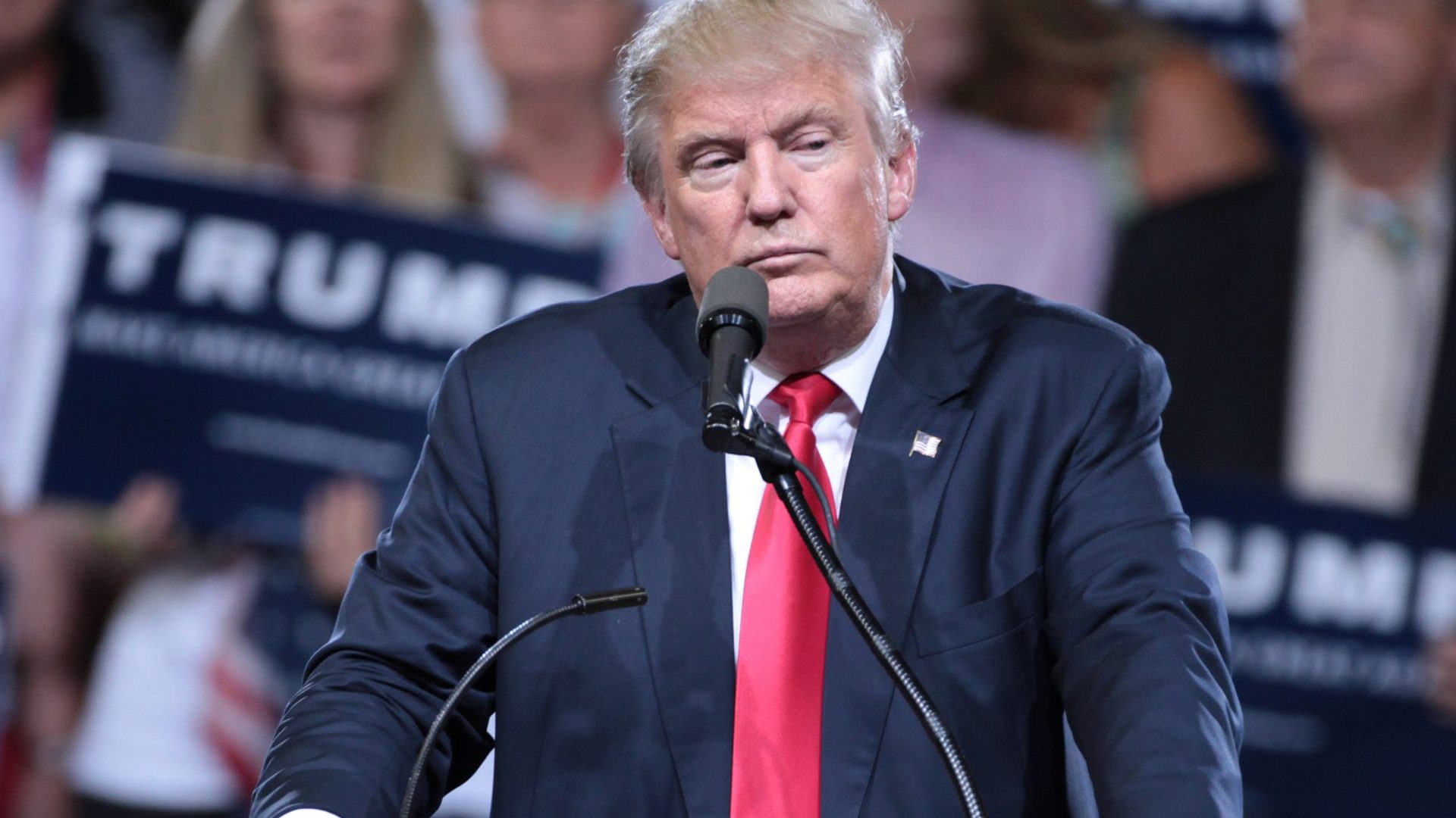 Man wearing blue suit stands at podium with microphone