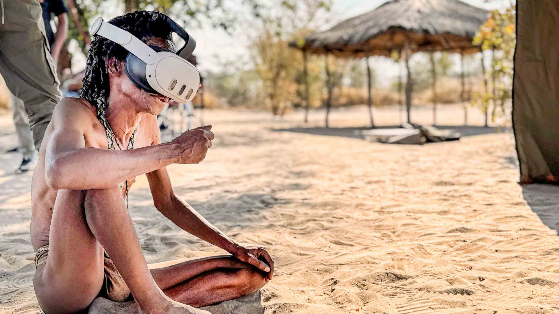 A person sits on the ground in a white VR headset.