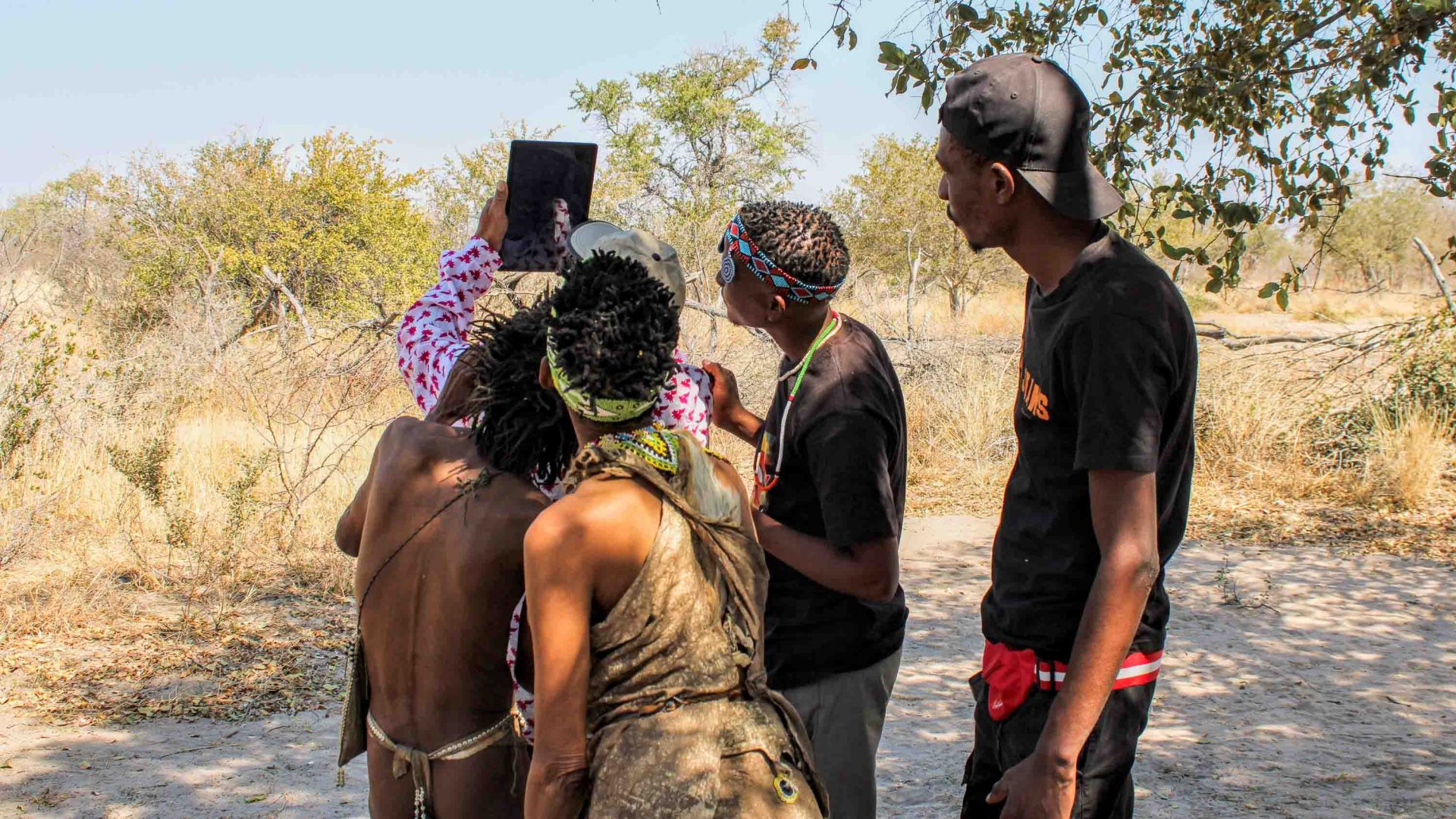 A group of 4 people look together at an app on a device.