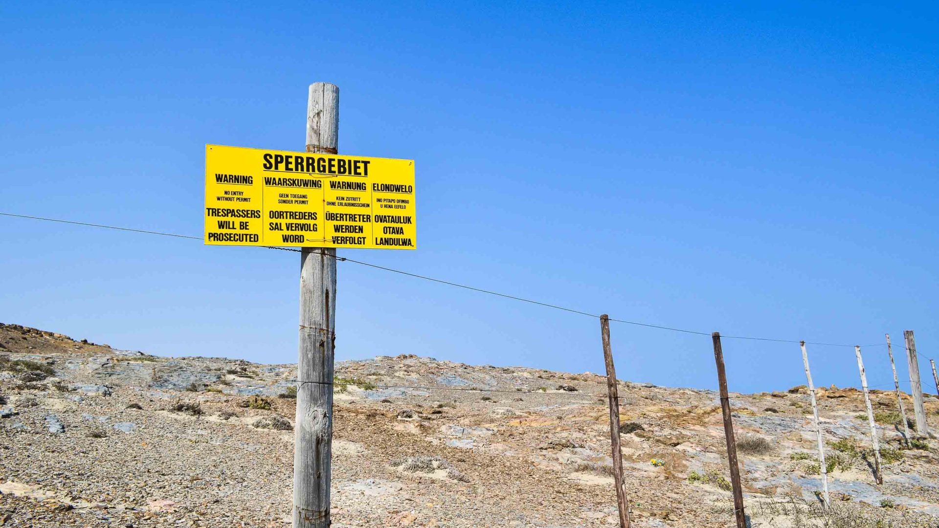 A yellow sign tells people not to enter the land.