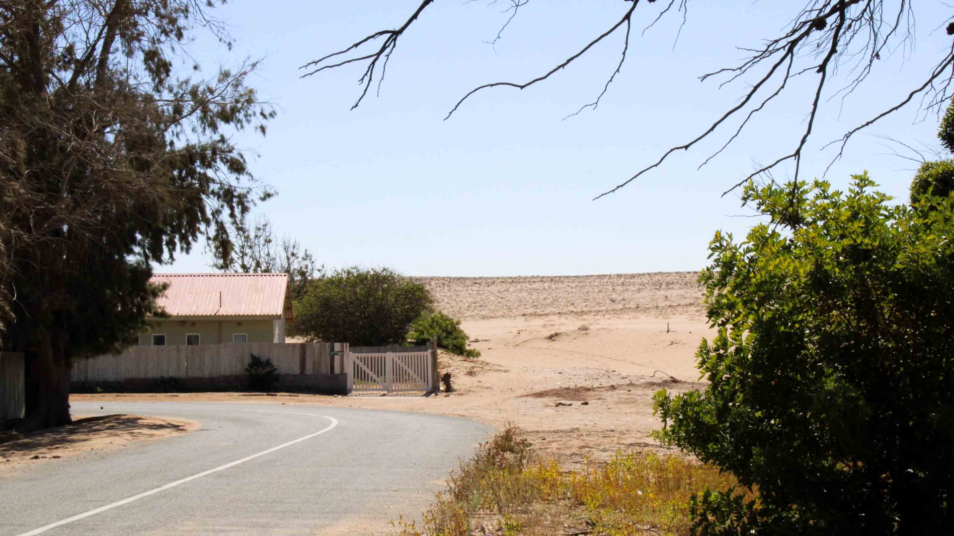 A street leads to a building, and then there is desert.