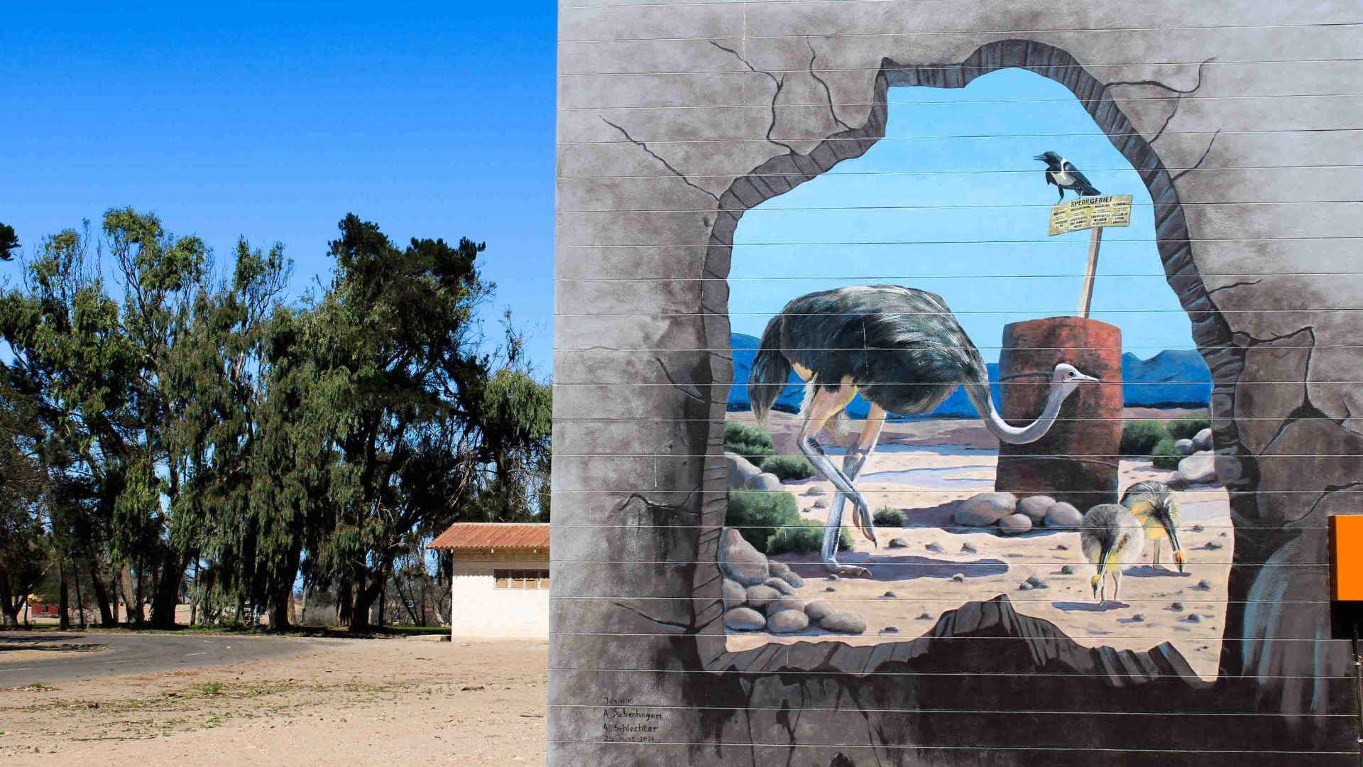 A mural on a wall and houses in the background.