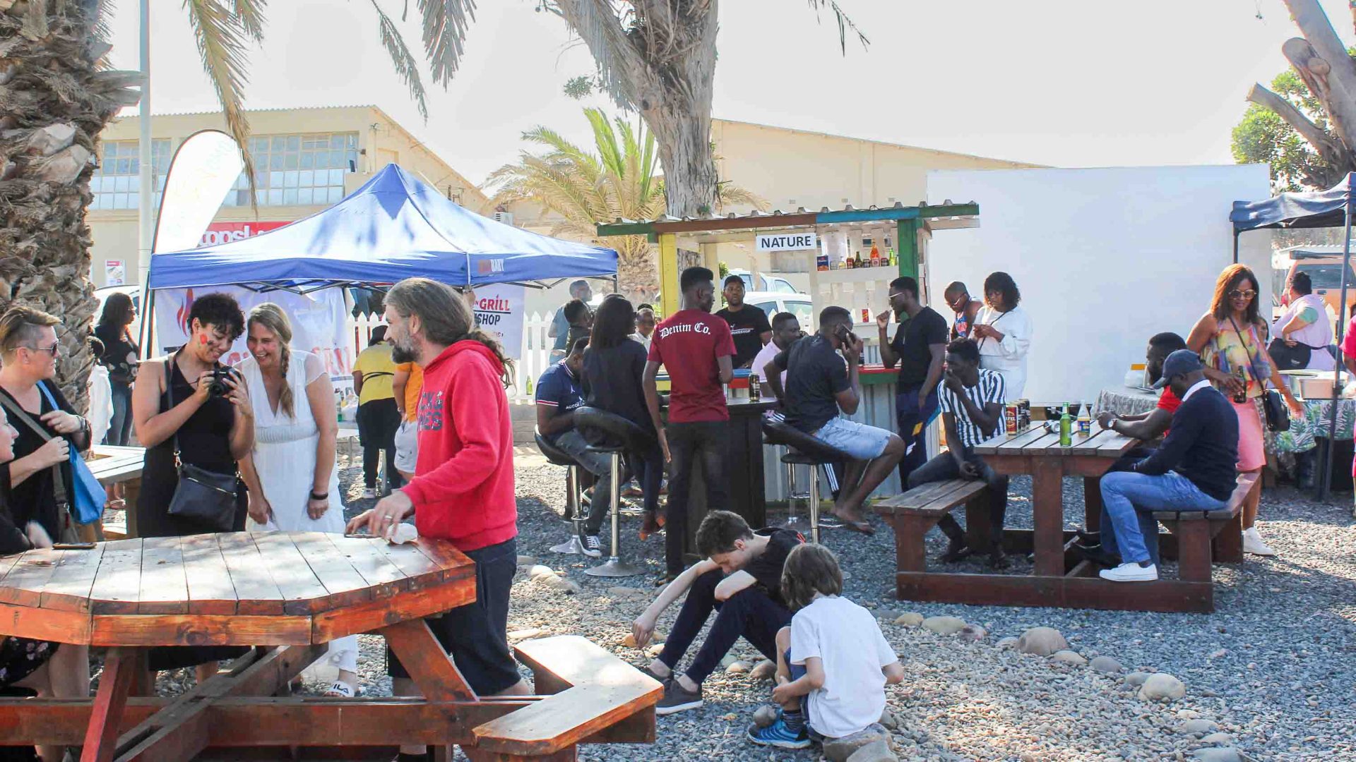 People gather at stalls and tables at a community market.