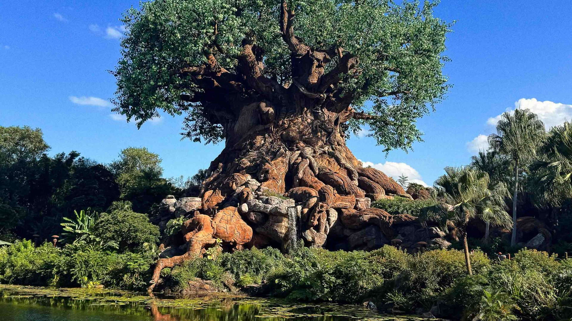 A fake tree next to a lake.