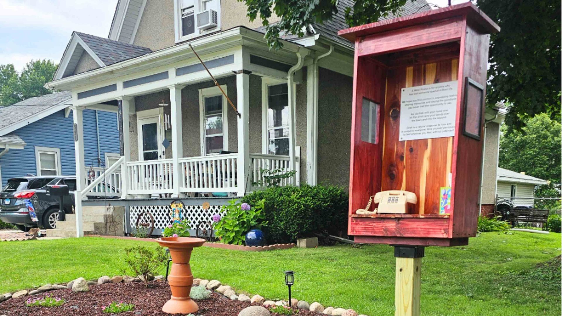A red phone box in the garden of someones home.