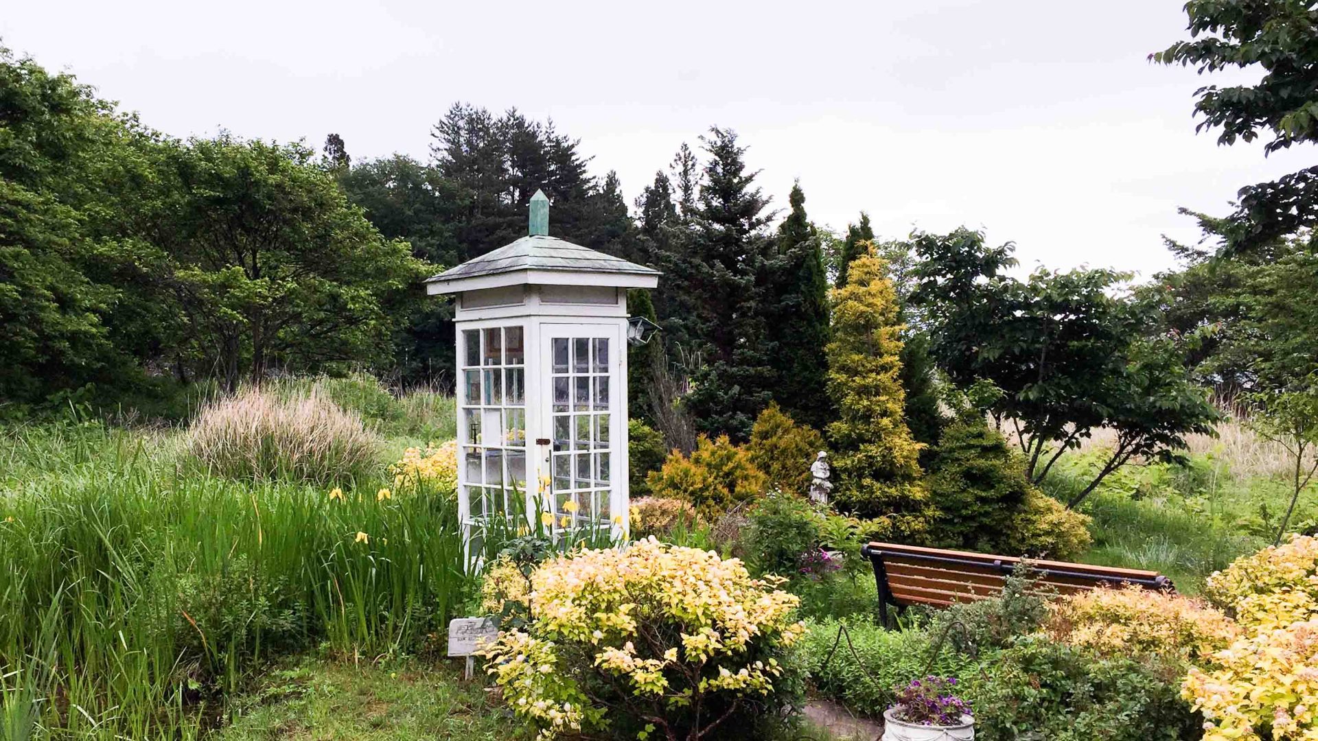 A white phone box in a landscaped garden.