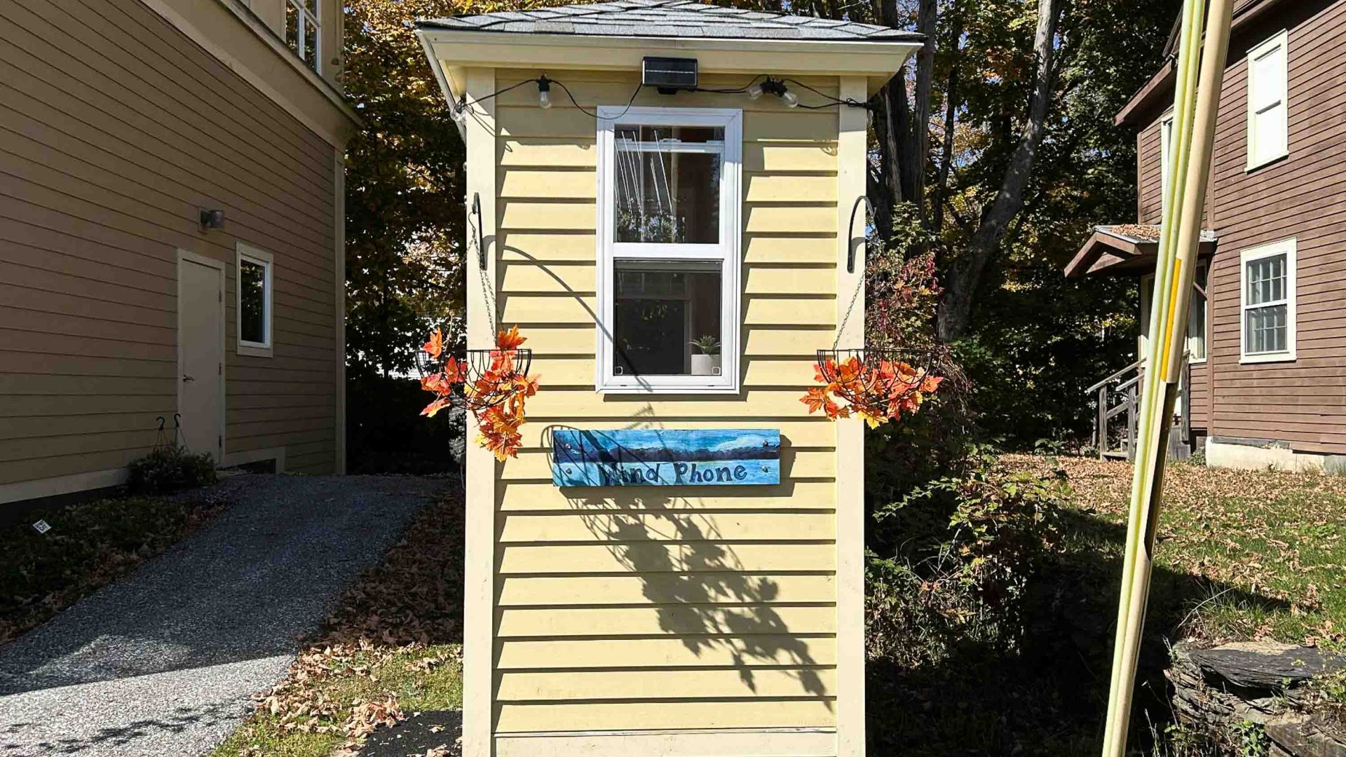 A cream coloured phone box alongside a building.