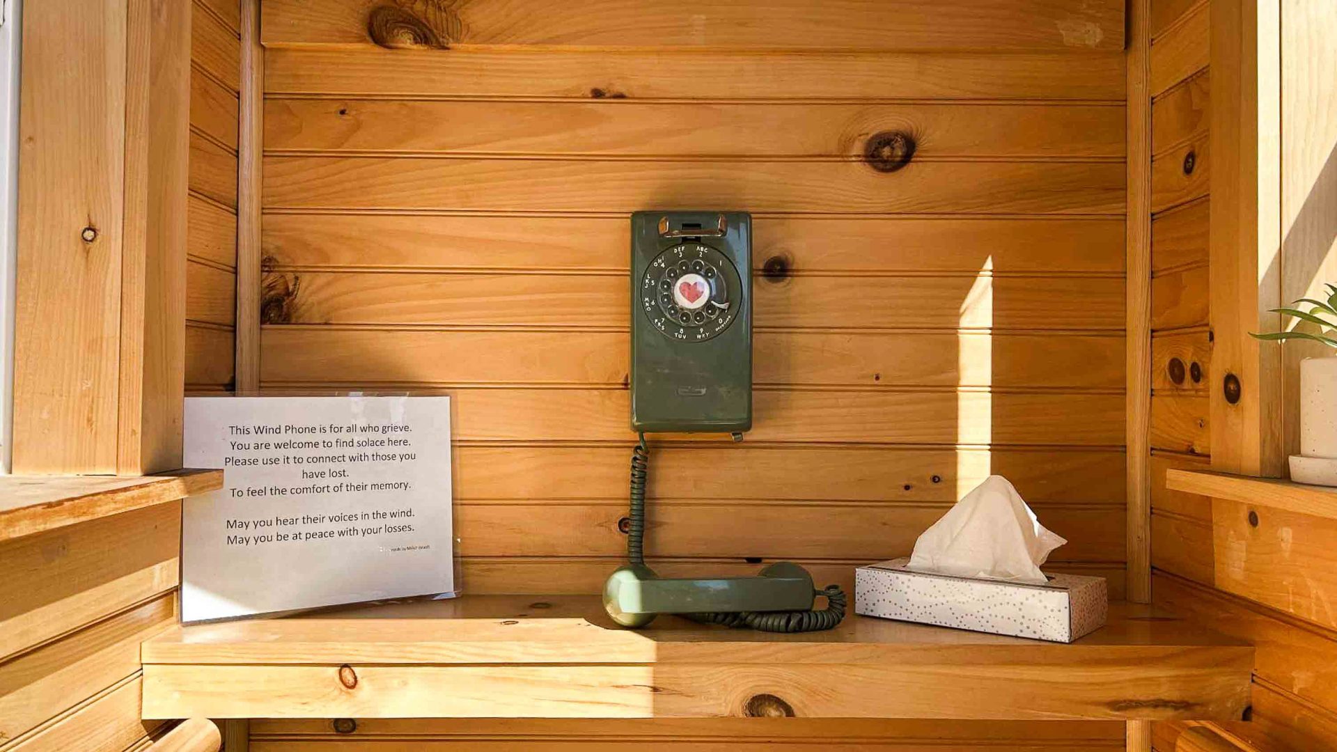 A green phone inside a wood panelled phone booth.
