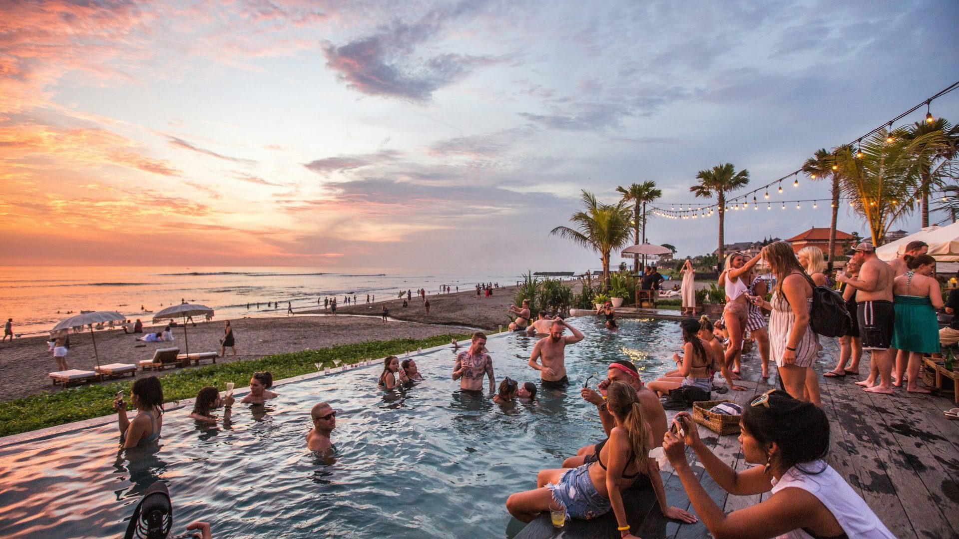 Crowd of tourists watch sunset from swimming pool