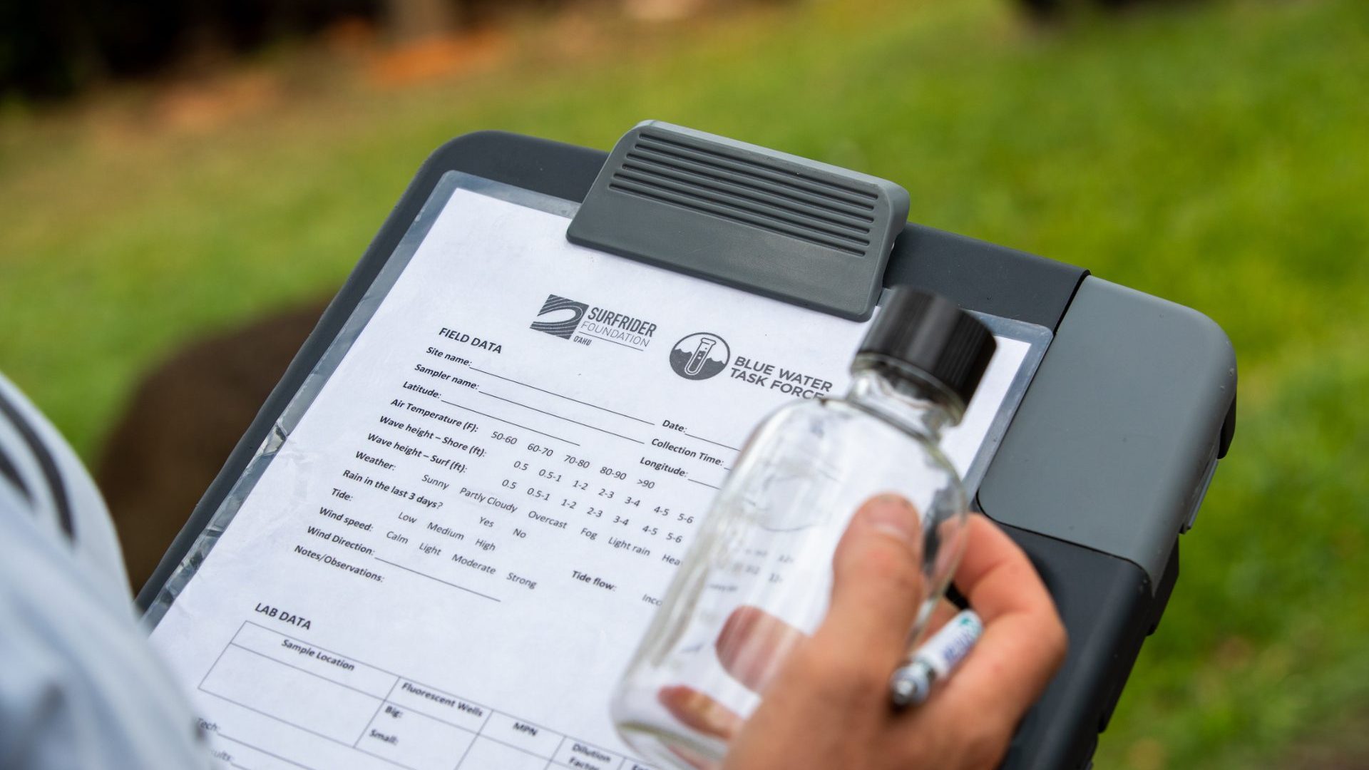 Hand holds clipboard with results of water quality testing