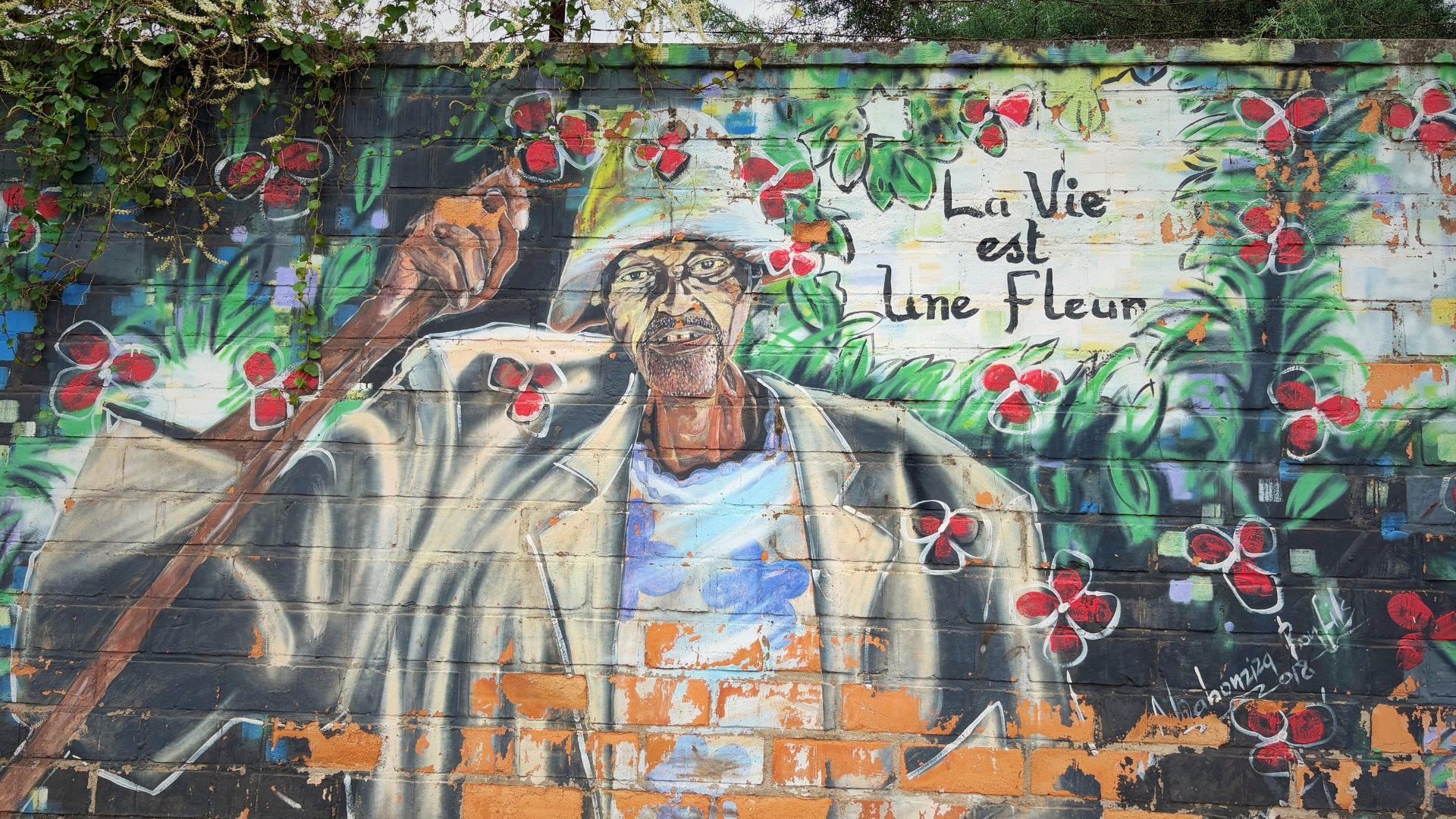 A colorful mural on a tree-lined street