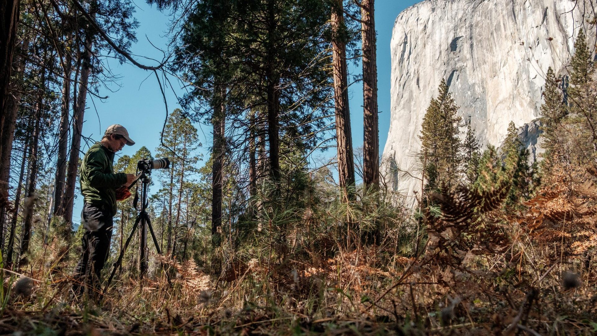 Man studies mountain using instrument.