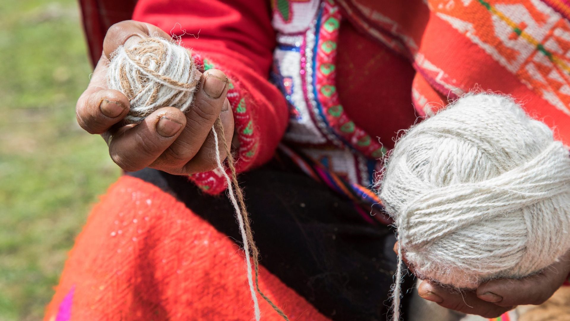 Hands hold a ball of white yarn.