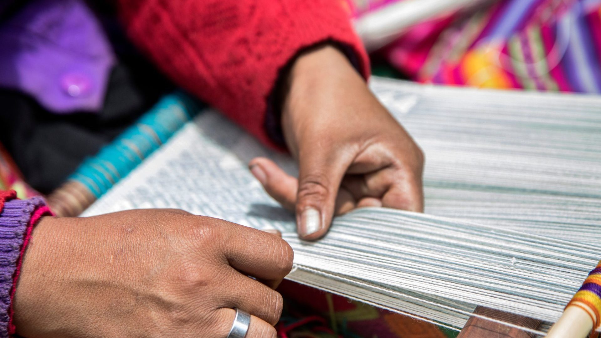 Hands weaving white yarn.