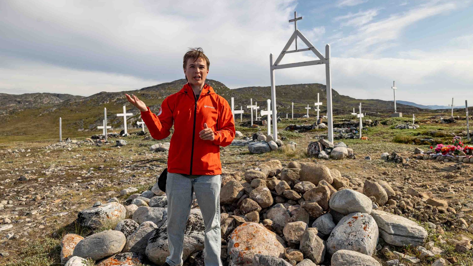 A guide in red talks at a cemetery.