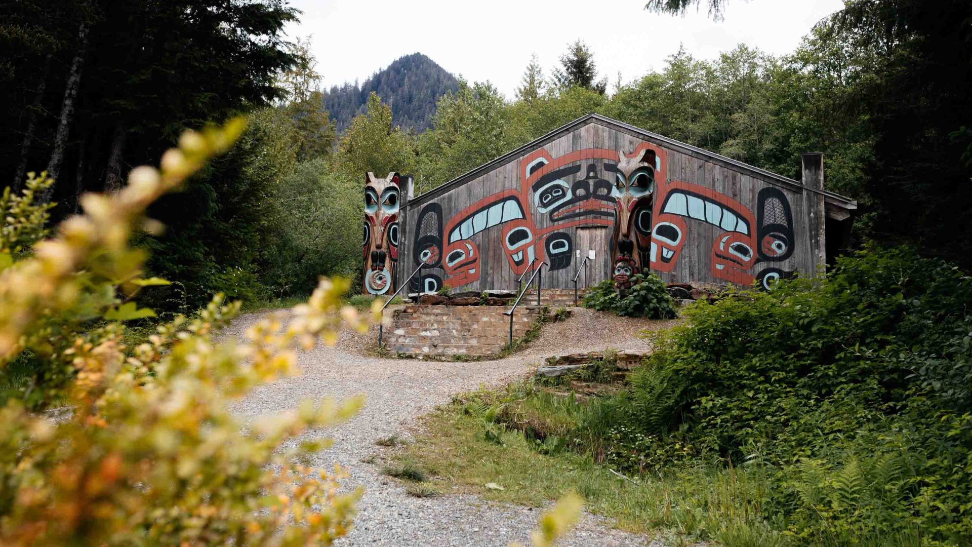 A wooden house painted in traditional Indigenous designs in a forest.