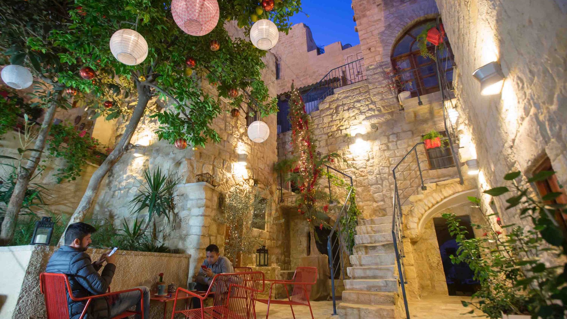 The interior courtyard of a hotel with stonework, soft lighting and lanterns.