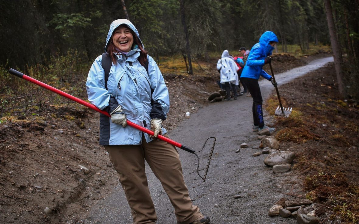 Woman smiles holding garden tool