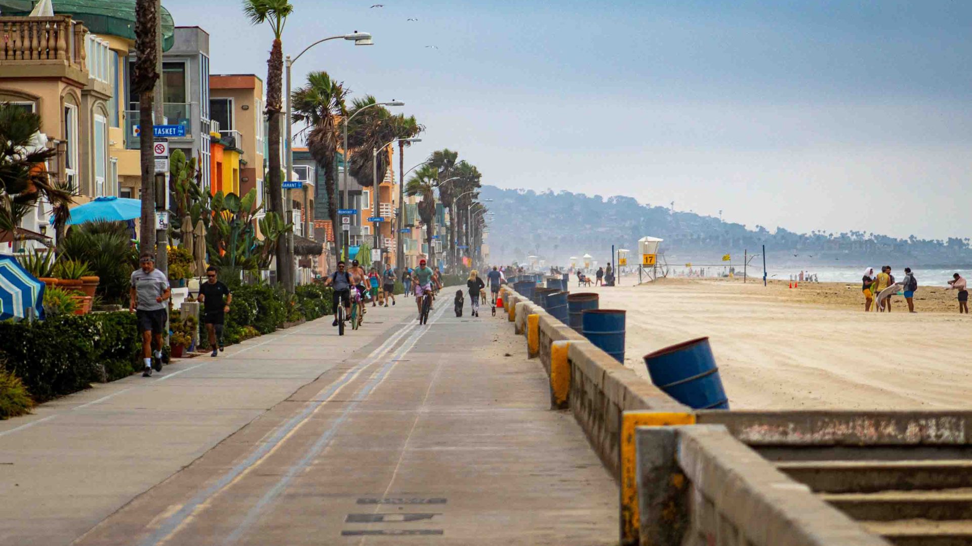A boardwalk lined with shops runs parallel to a beach.