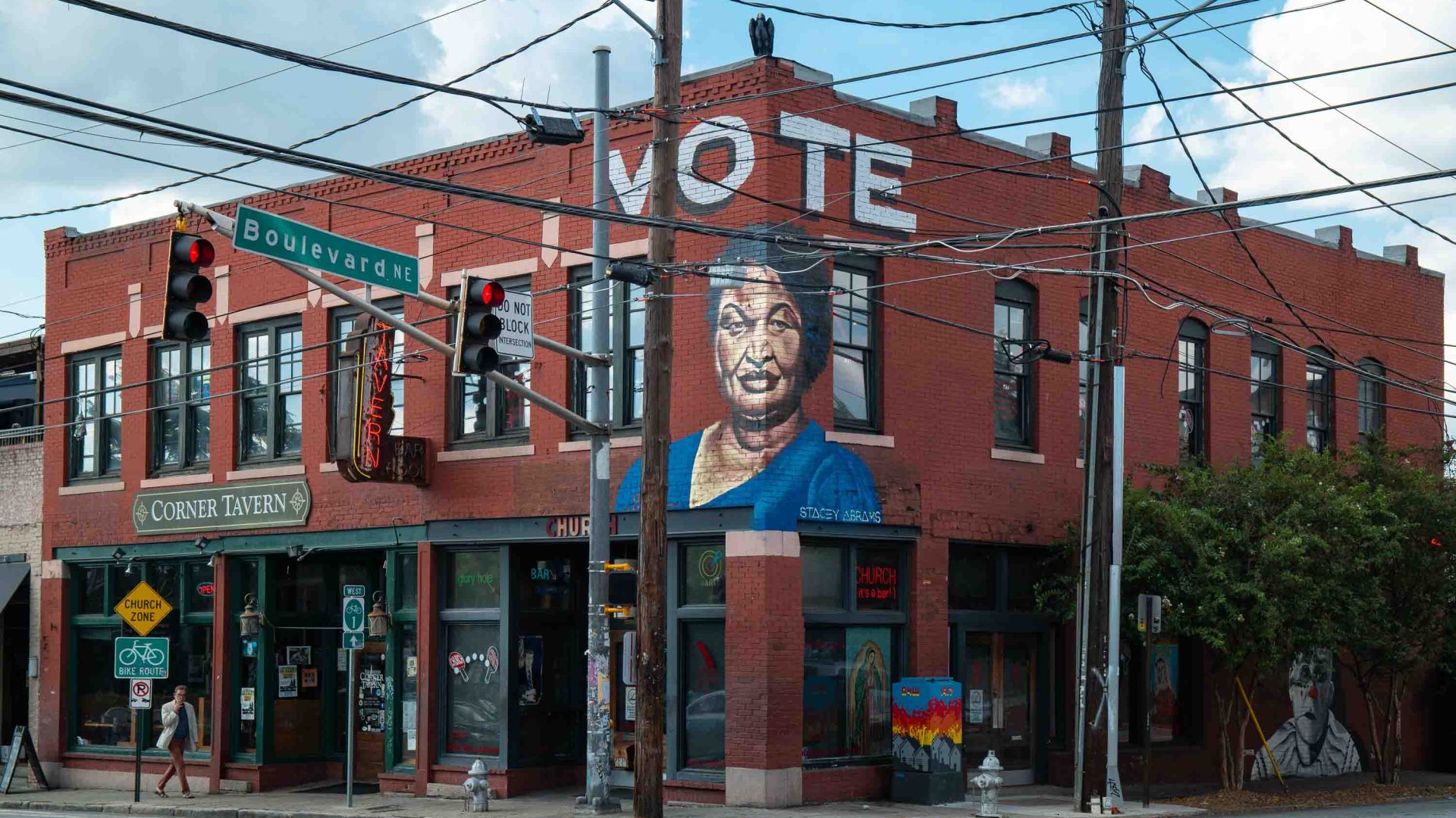 The exterior of a building made of brick with a mural on it and the word 'Vote'.