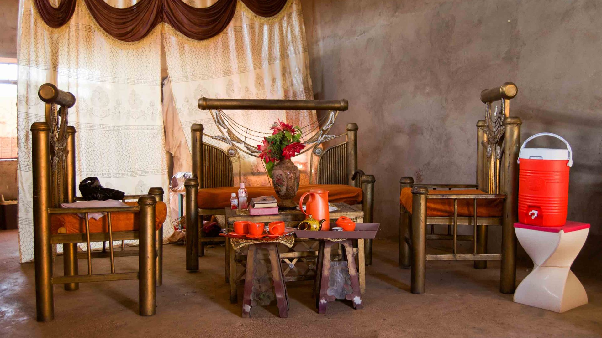 A beautifully adorned living space with tea cups on the table and orange furnishings.