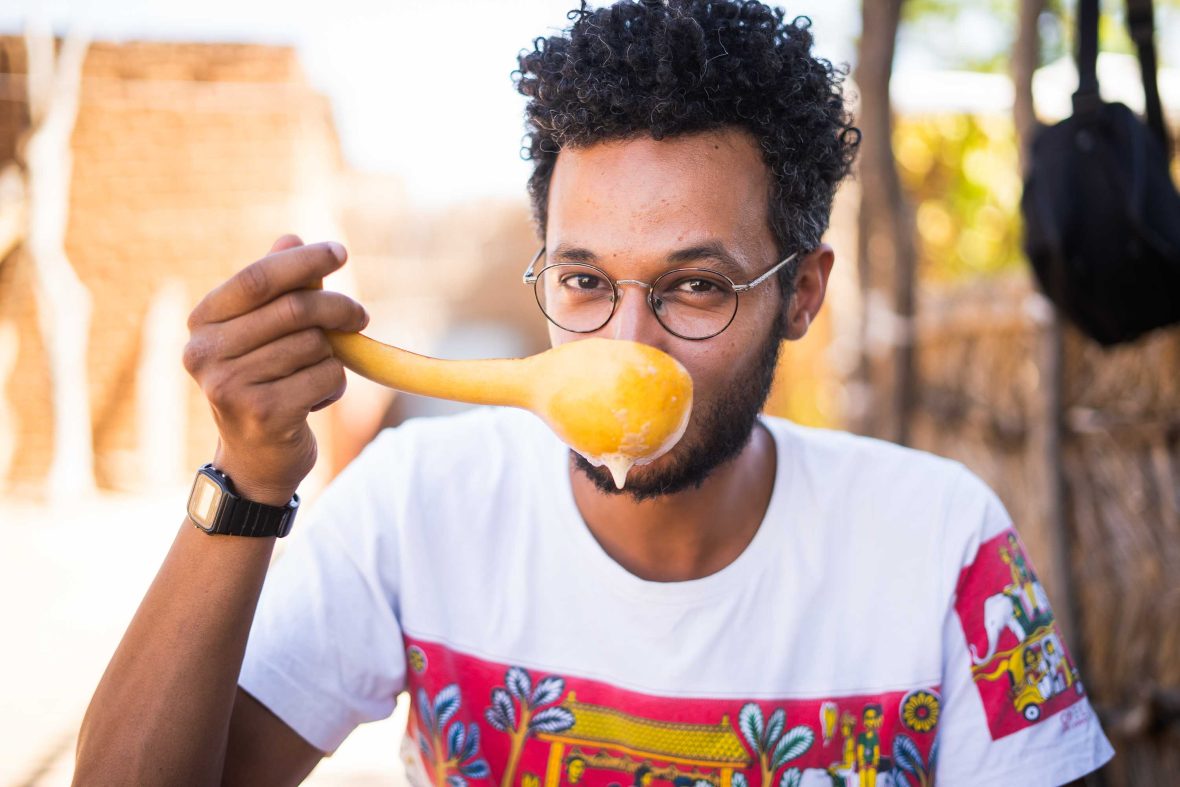 A man sips from a large spoon.