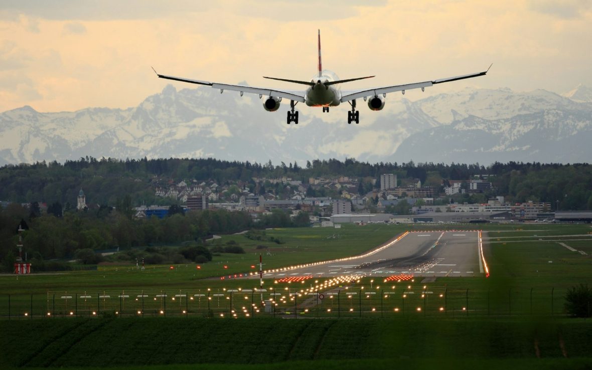 A plane takes off with a mountain view in the distance.