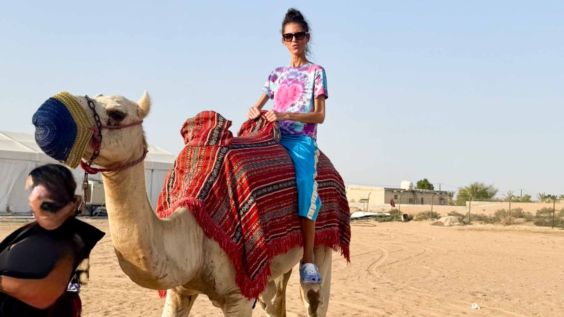A woman on a camel in a desert setting.