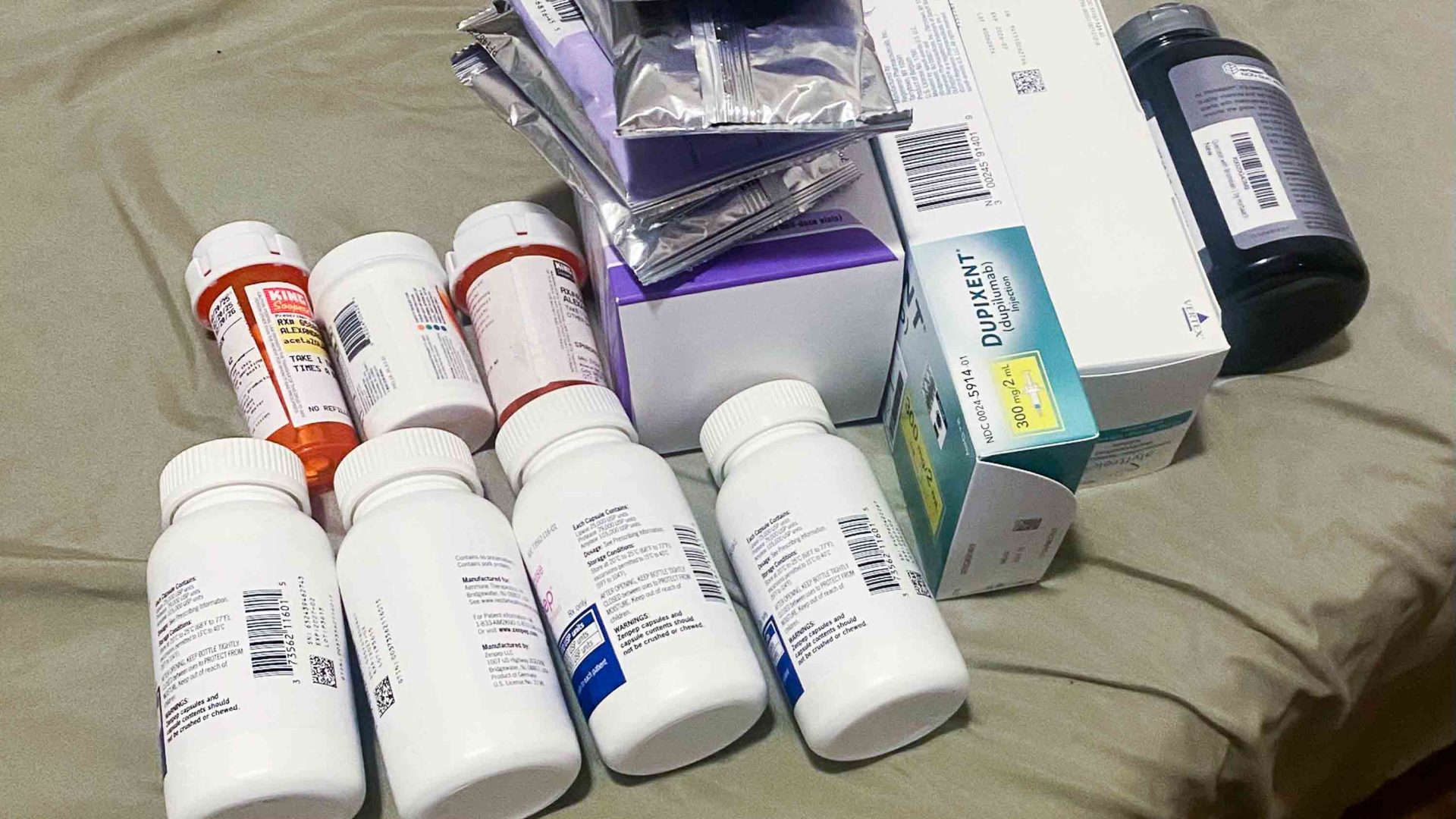 A pile of pill bottles on a bed.