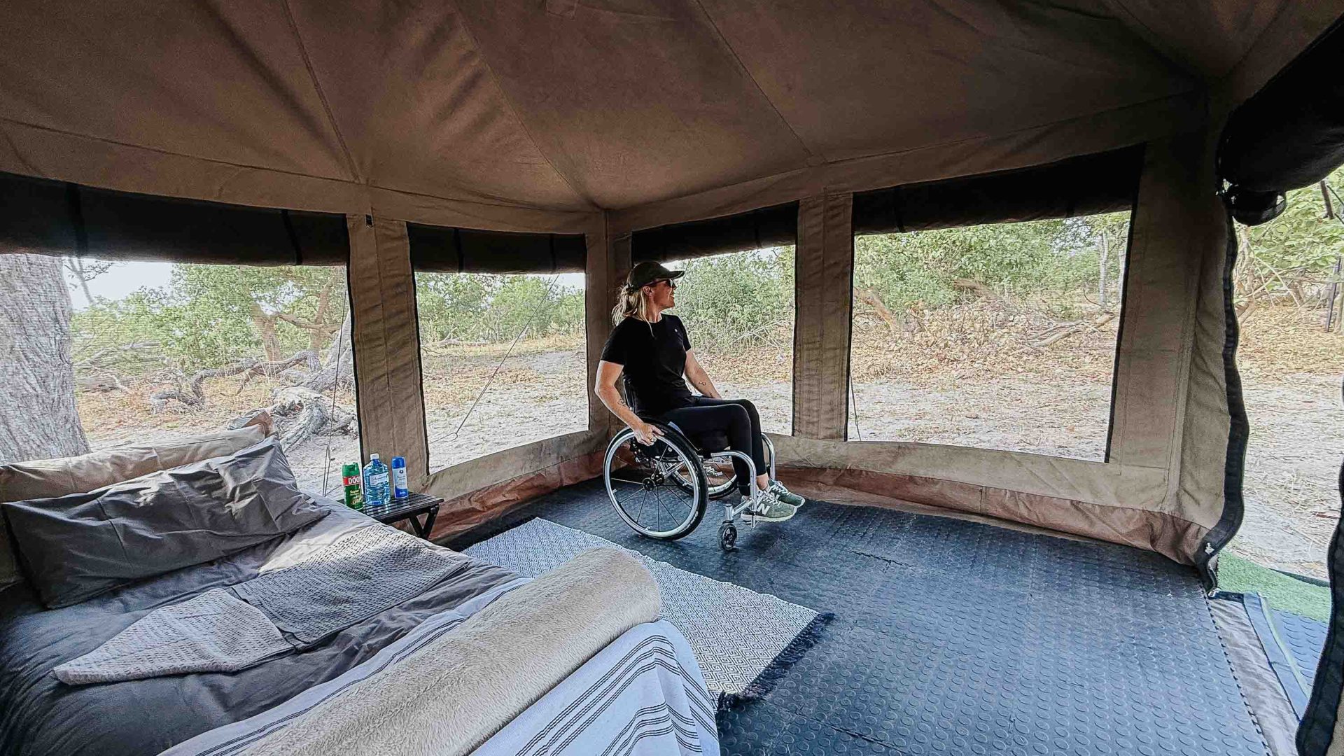 A woman in a wheelchair looks around the interior of her tent.