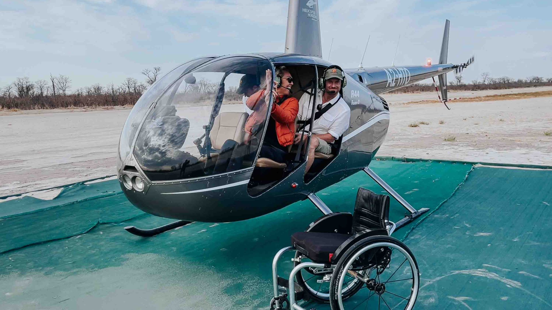 A woman and a man smile from the interior of a helicopter.