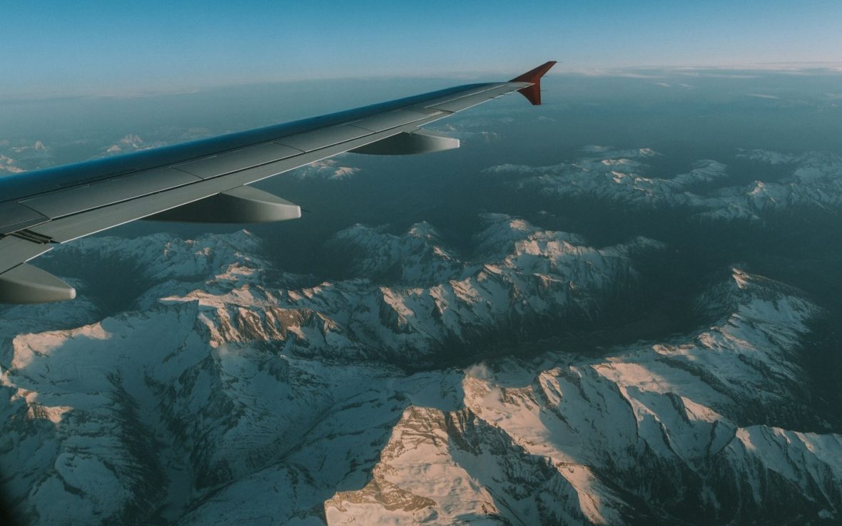 The wing of a plane flying over a mountain range