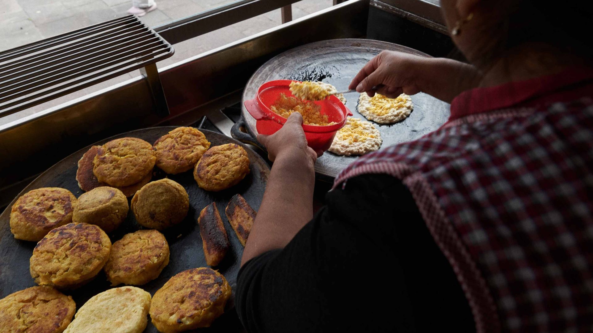 A woman prepares food over a stove set up outside.