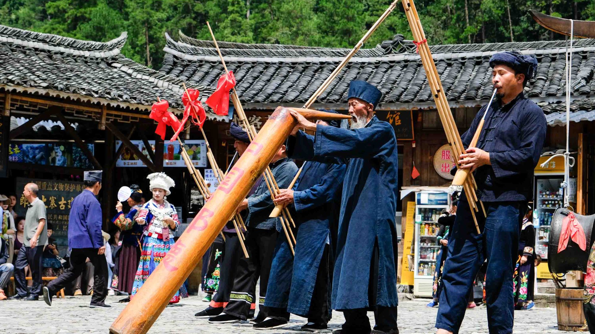 Men in blue play instruments in a town square.