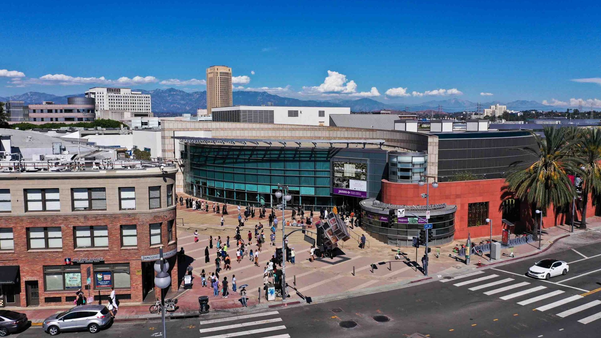 Photo taken from a height of people in a street near a museum and other buildings.