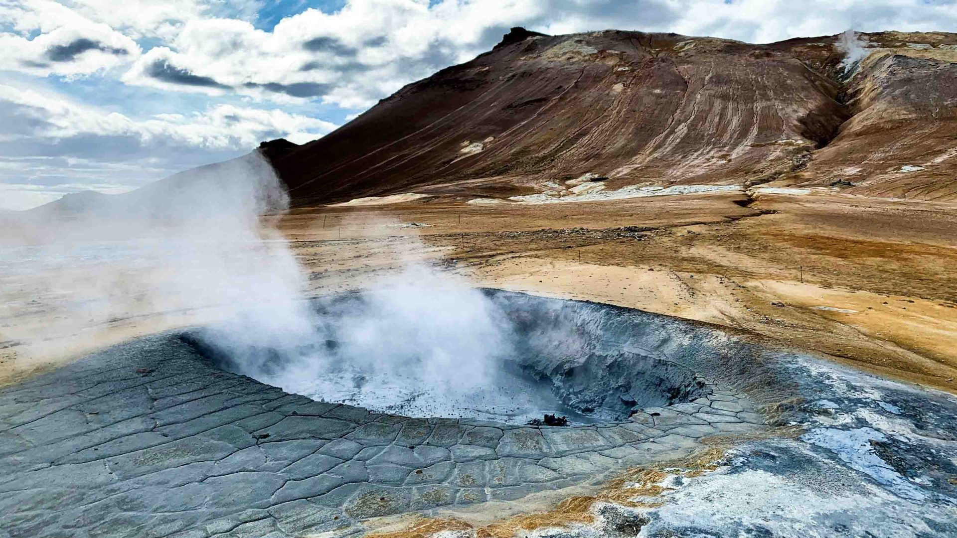 A boiling mud pit with steam coming from it.
