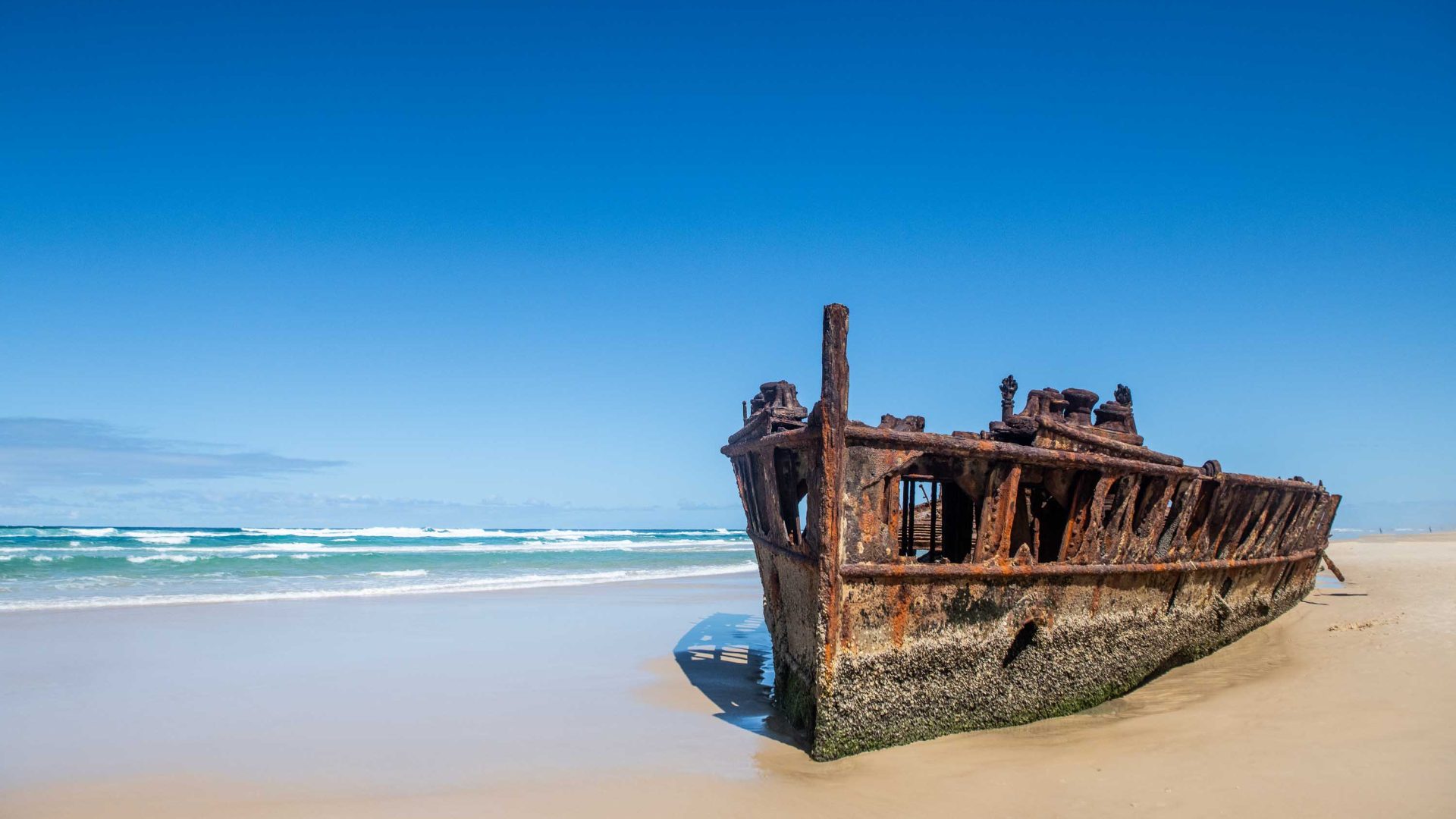 A rusty shipwreck on a beach.