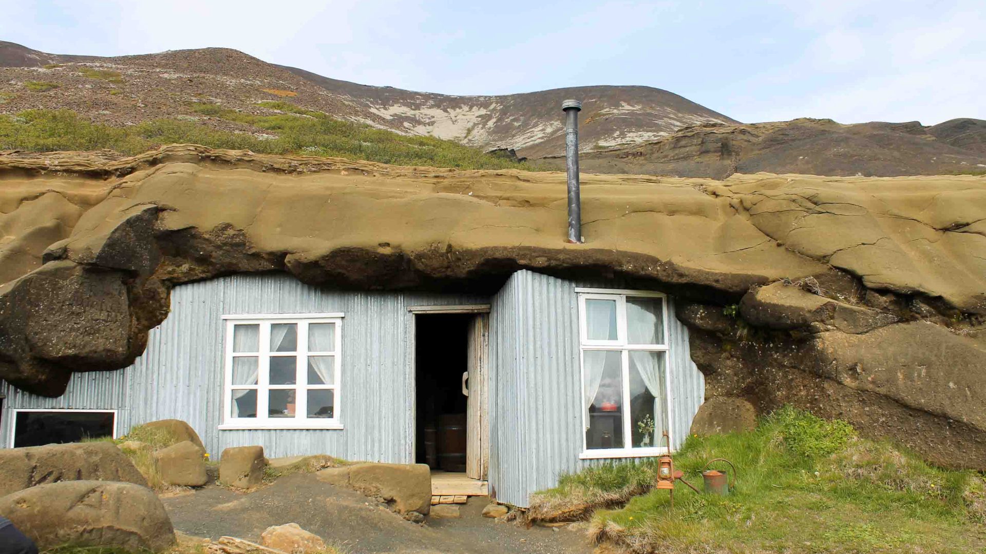 A small house underneath a rocky shelf.