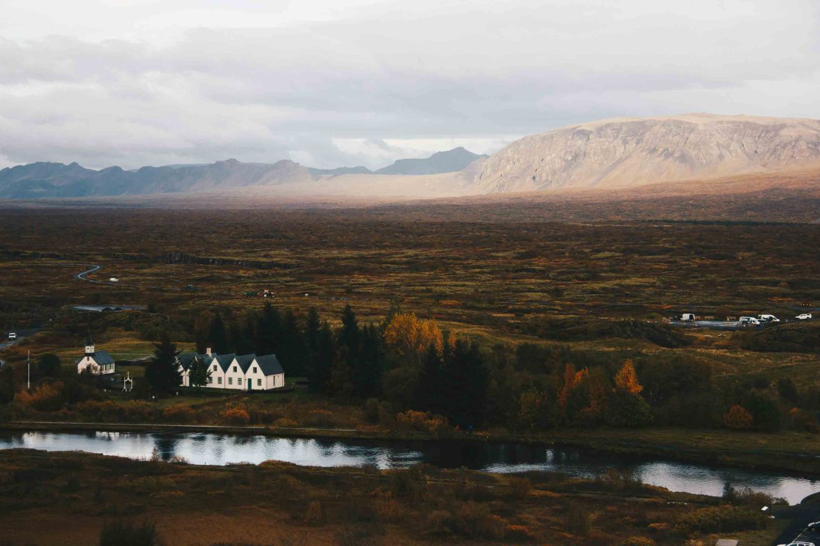 A house alongside a lake in a valley with mountains.
