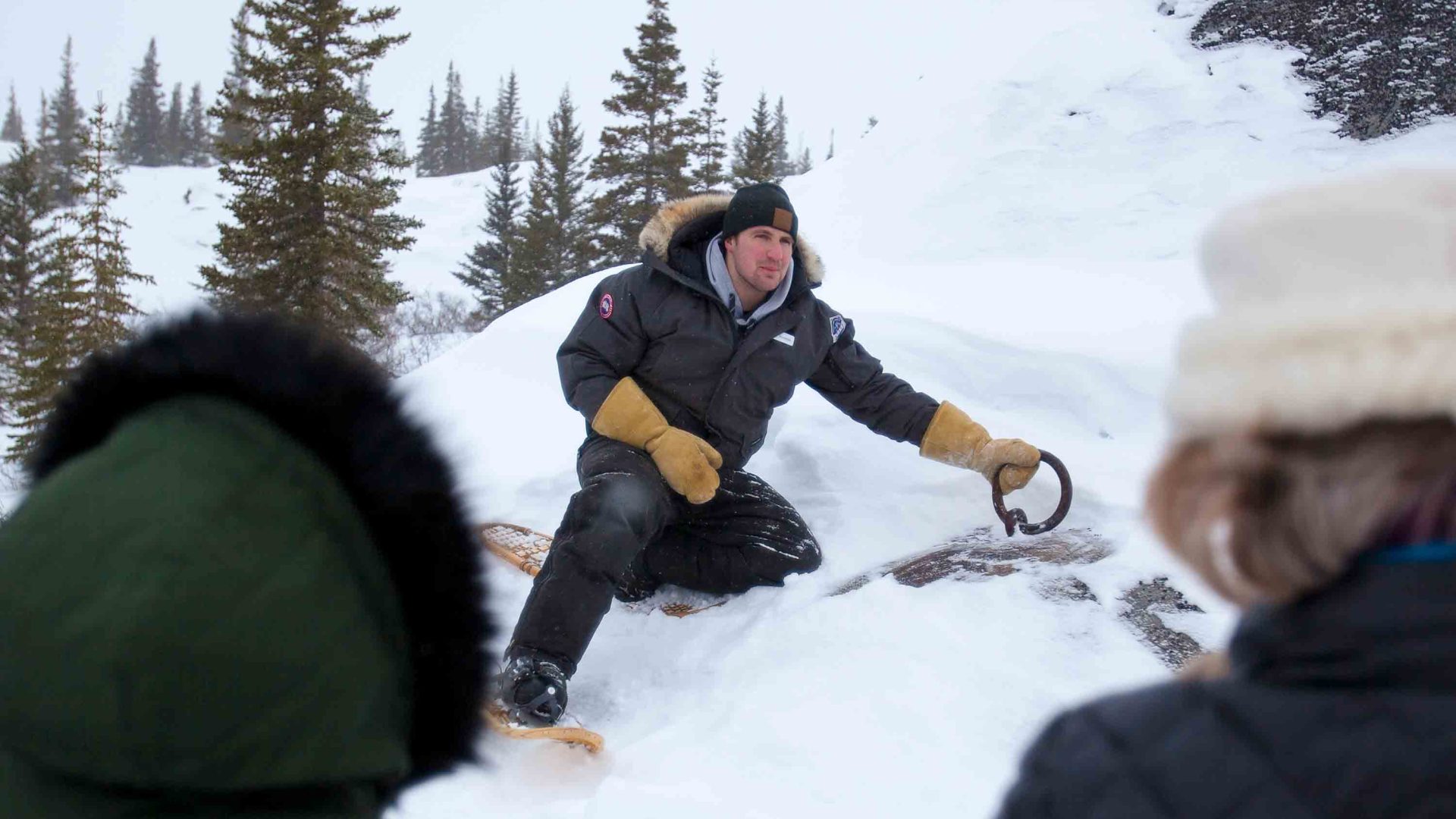 A man talks to a group while seated in the snow.